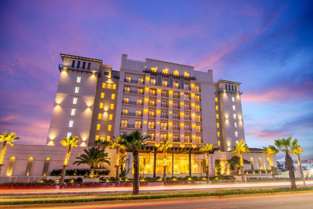 un grand bâtiment avec des palmiers devant lui dans l'établissement Torre Lucerna Hotel Ensenada, à Ensenada