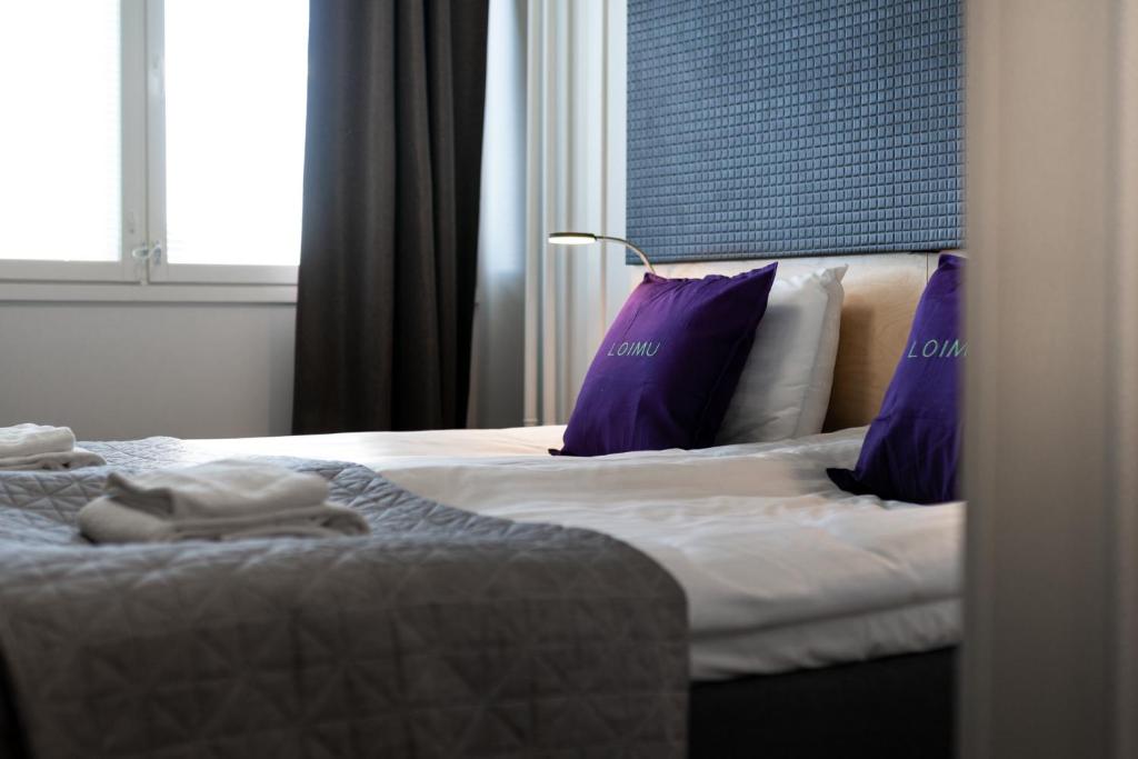 a hotel room with two beds with purple pillows at Hotelli Loimu in Raisio