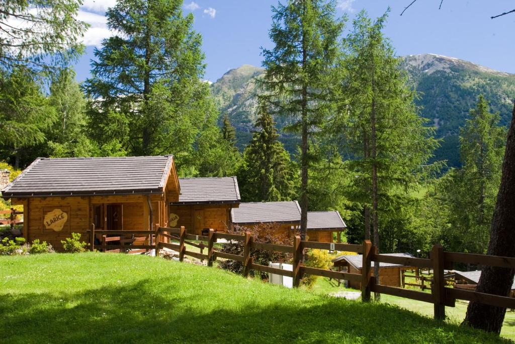 a log cabin in the mountains with a fence at Camping Village Yolki Palki in Bognanco