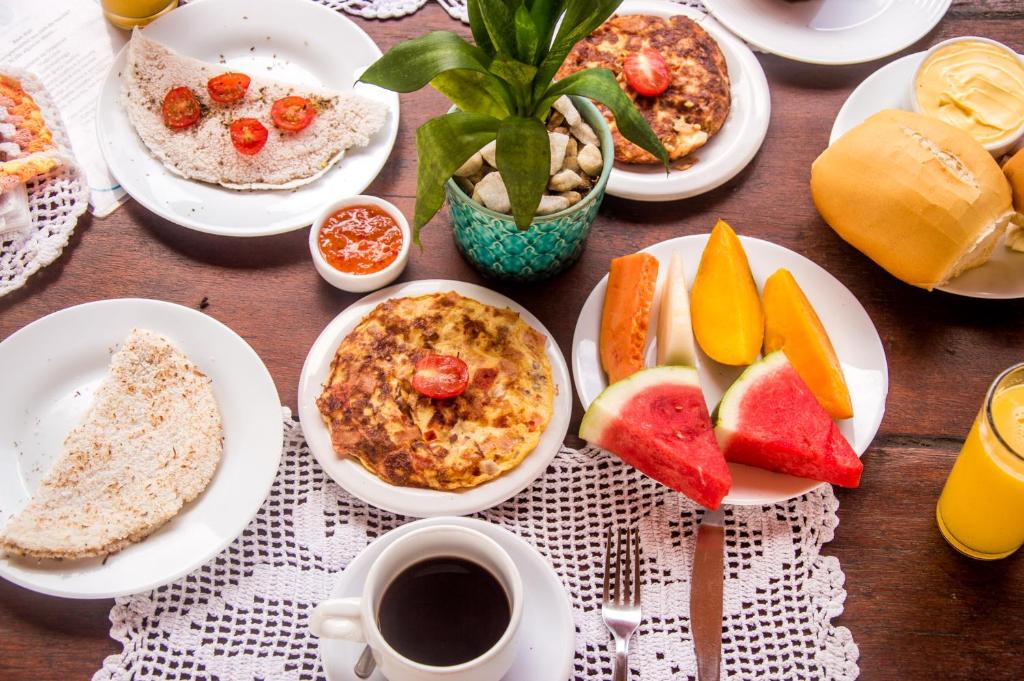 a table with plates of breakfast foods and a cup of coffee at A casa é sua! in Jericoacoara