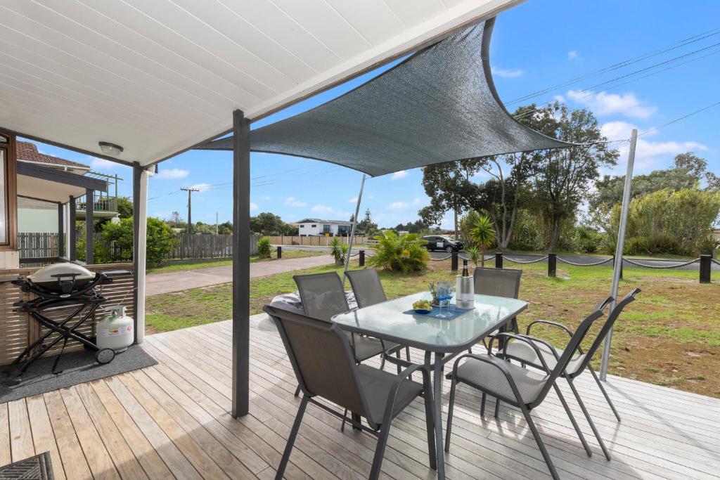 a patio with a table and chairs on a deck at Bream Bay Sands - Ruakaka Holiday Home in Ruakaka