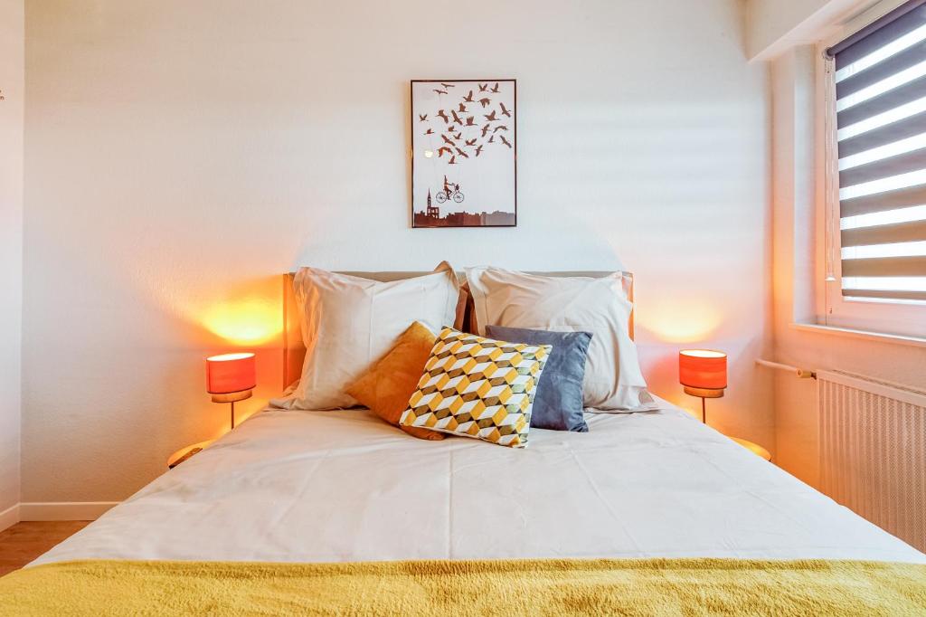 Un dormitorio con una cama con almohadas. en AlsaceTime, CENTRE Parking gratuit, TRAM WIFI, Fibre Orange, espace de travail en Estrasburgo