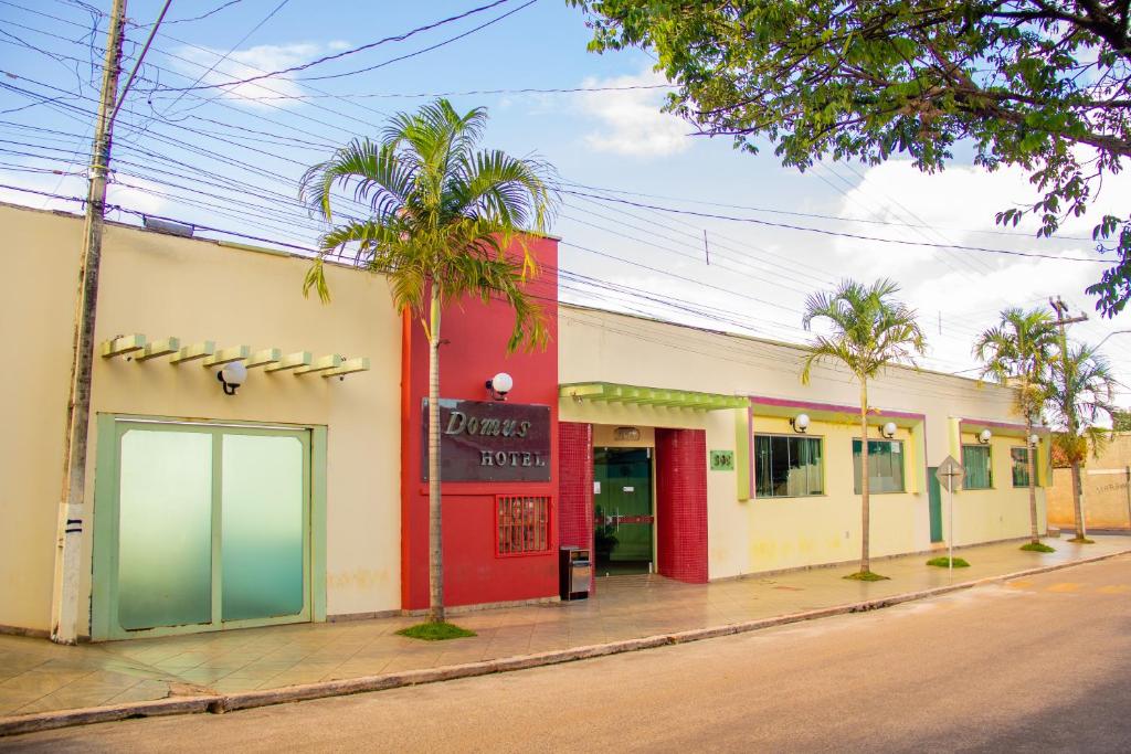 a building on the side of a street with palm trees at Domus Hotel Trindade Canaã dos Carajás in Canaã dos Carajás