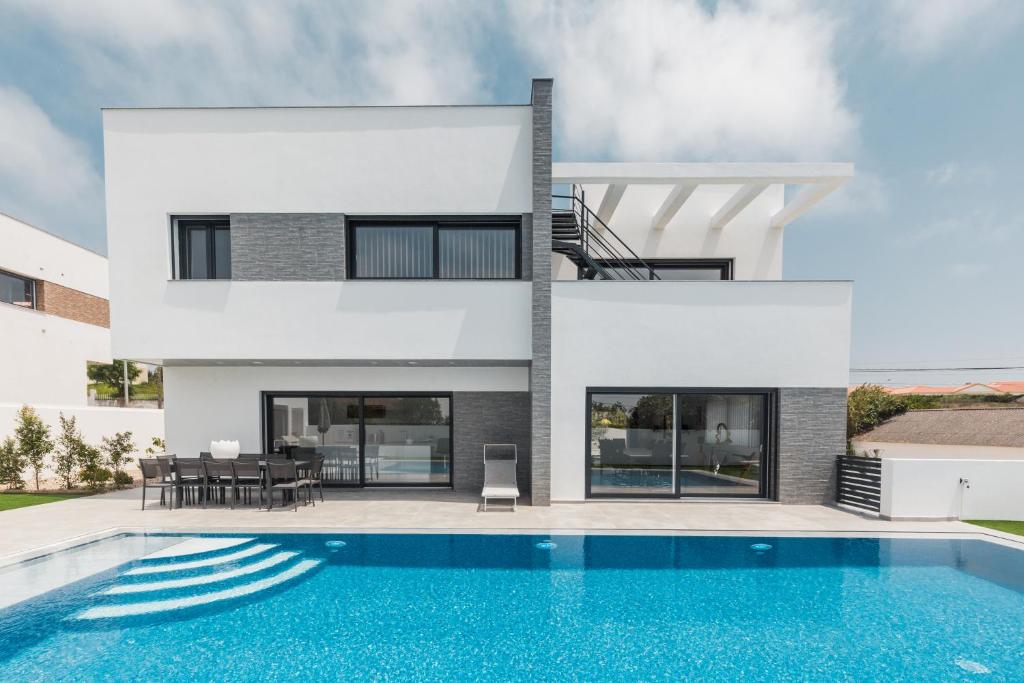 a house with a swimming pool in front of it at Chill House - Luxury house in Mariquiteira