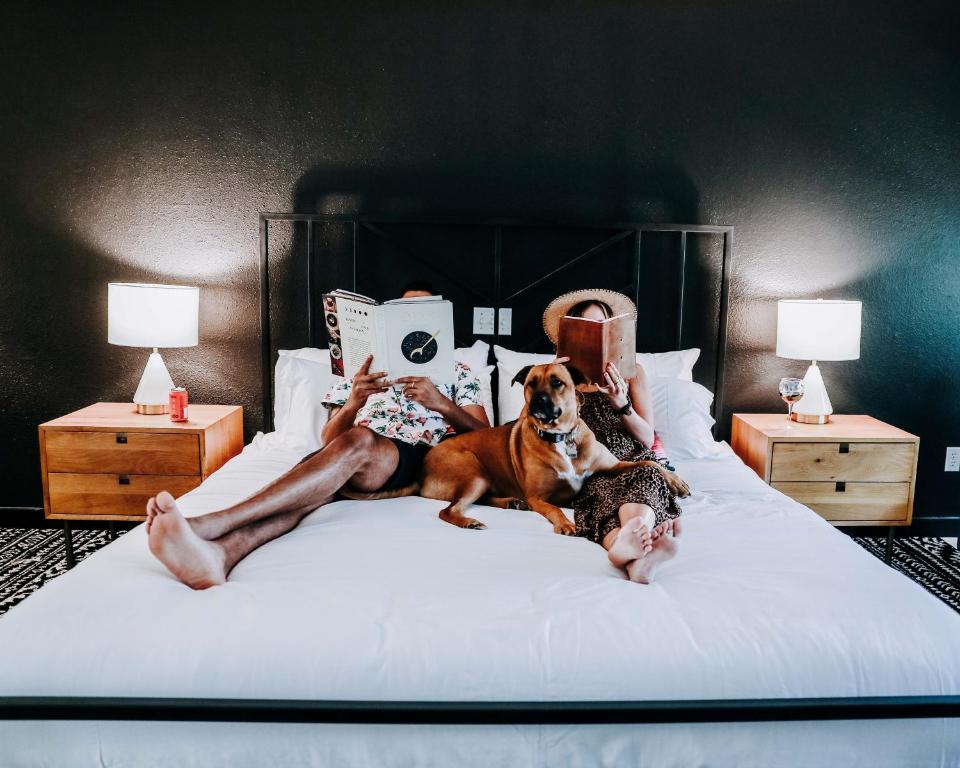 a man and woman laying on a bed with a dog at Wimberley Inn in Wimberley