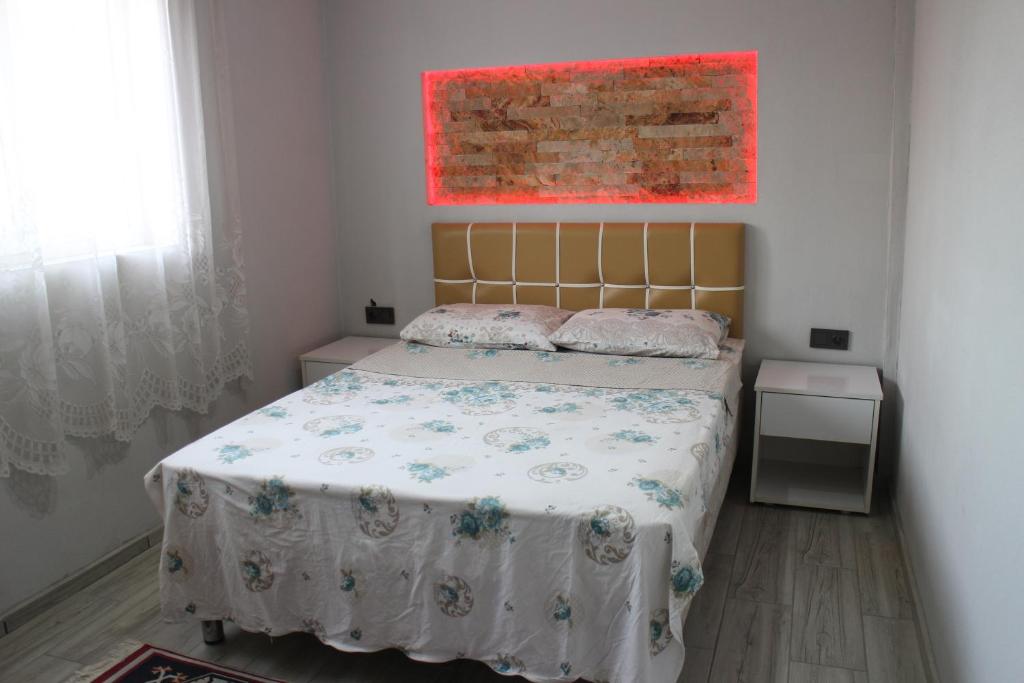 帕莫卡萊的住宿－Karaca Termal Pansiyon，卧室配有一张床,墙上挂有绘画作品