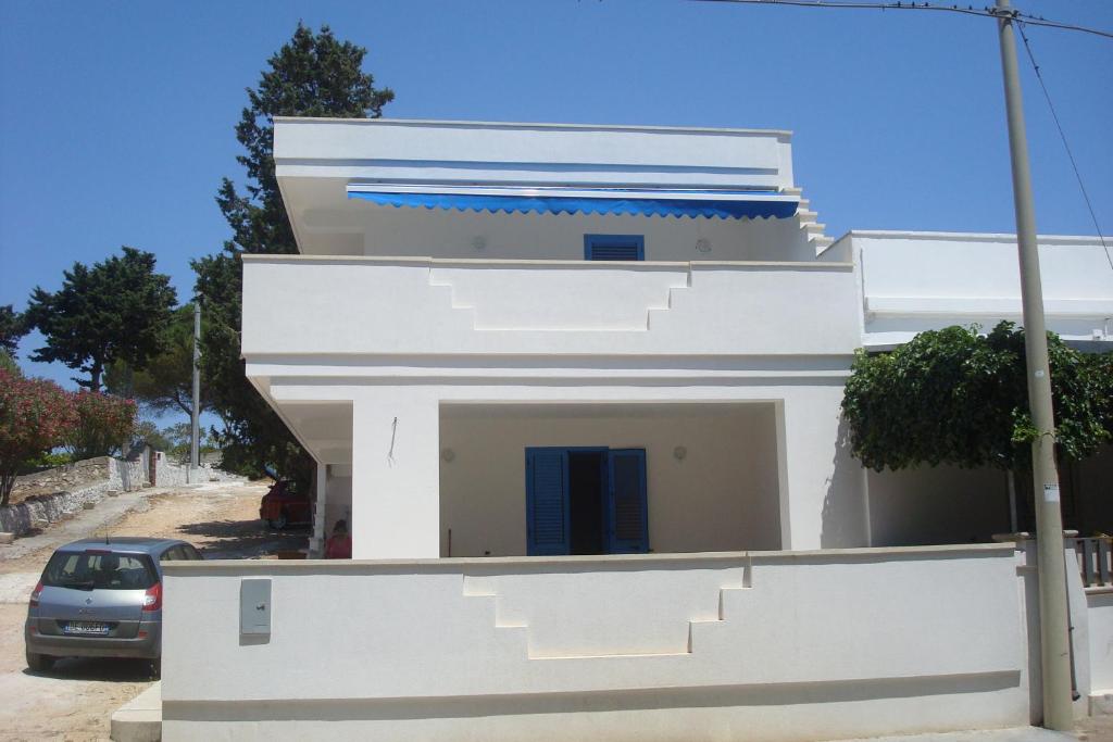 Una casa blanca con escaleras al costado. en Casa Azzurra Felloniche, en Castrignano del Capo