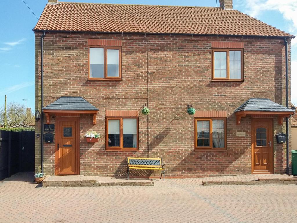 a brick house with a bench in front of it at Gough Bank in Bridlington