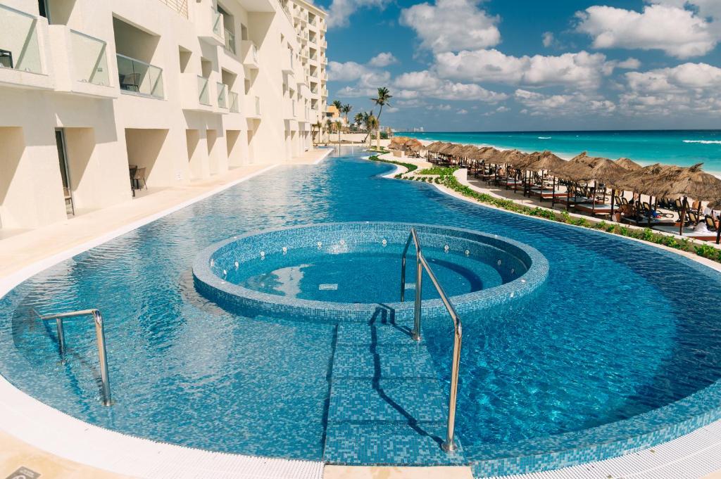 a swimming pool next to a building and the ocean at Emporio Cancun - Buy All Inclusive Option in Cancún