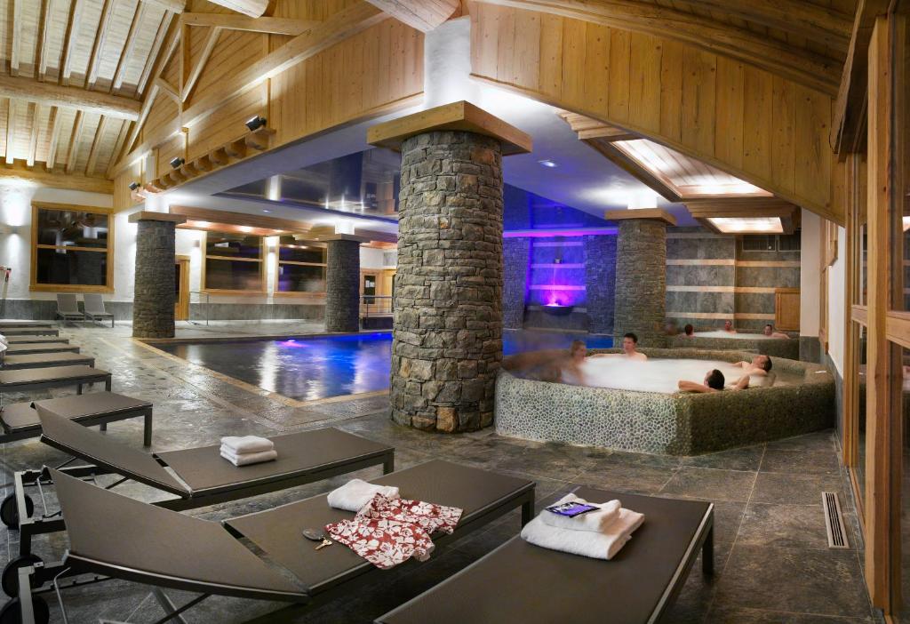 a hotel lobby with a hot tub with two people in it at CGH Résidences & Spas Les Granges Du Soleil in La Plagne