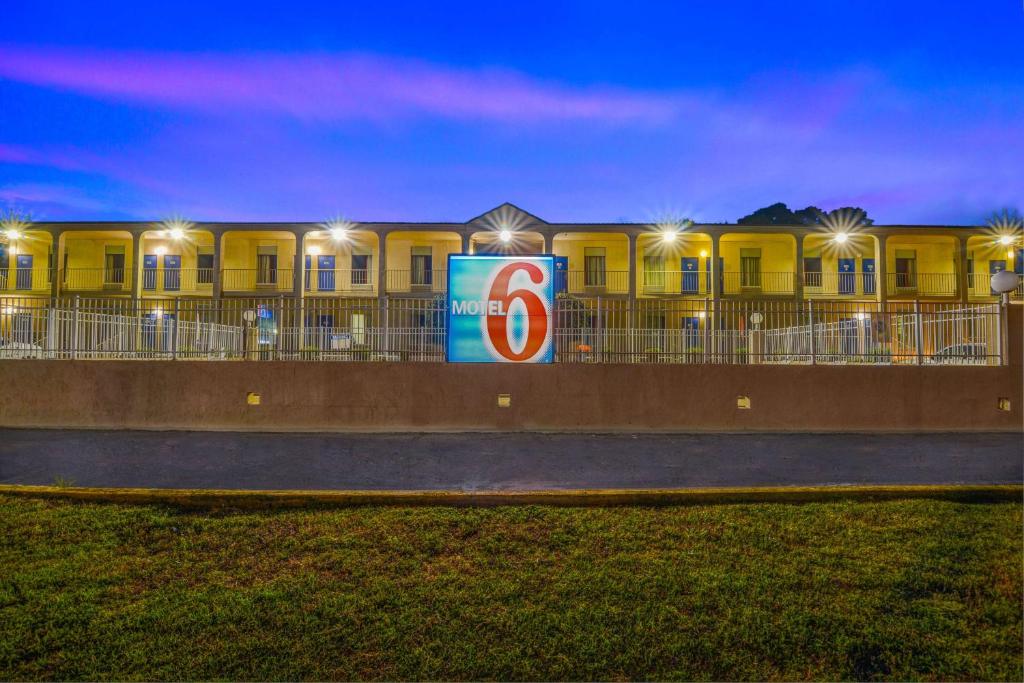 un edificio amarillo con un cartel delante en Motel 6-Americus, GA, en Americus