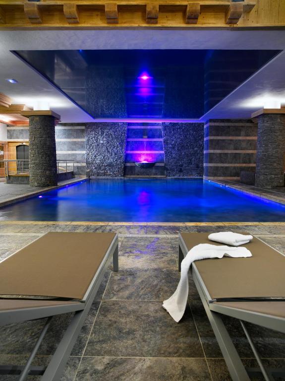 a swimming pool with blue water in a building at CGH Résidences & Spas Les Granges Du Soleil in La Plagne