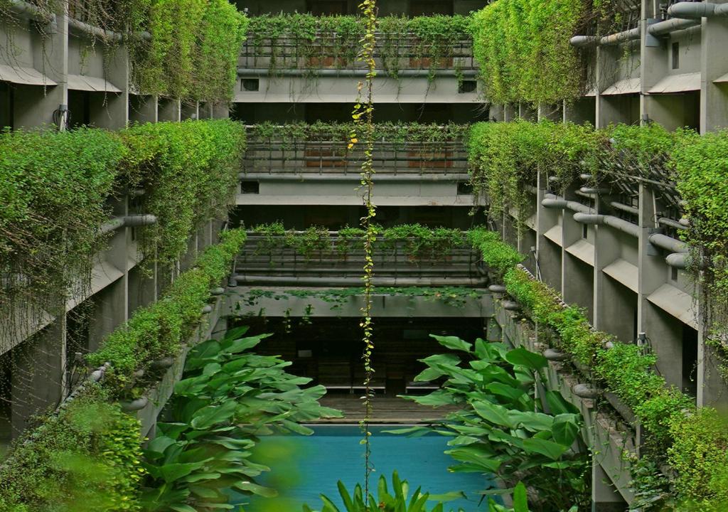 a building with a pool of water and plants at Greenhost Boutique Hotel Prawirotaman in Yogyakarta