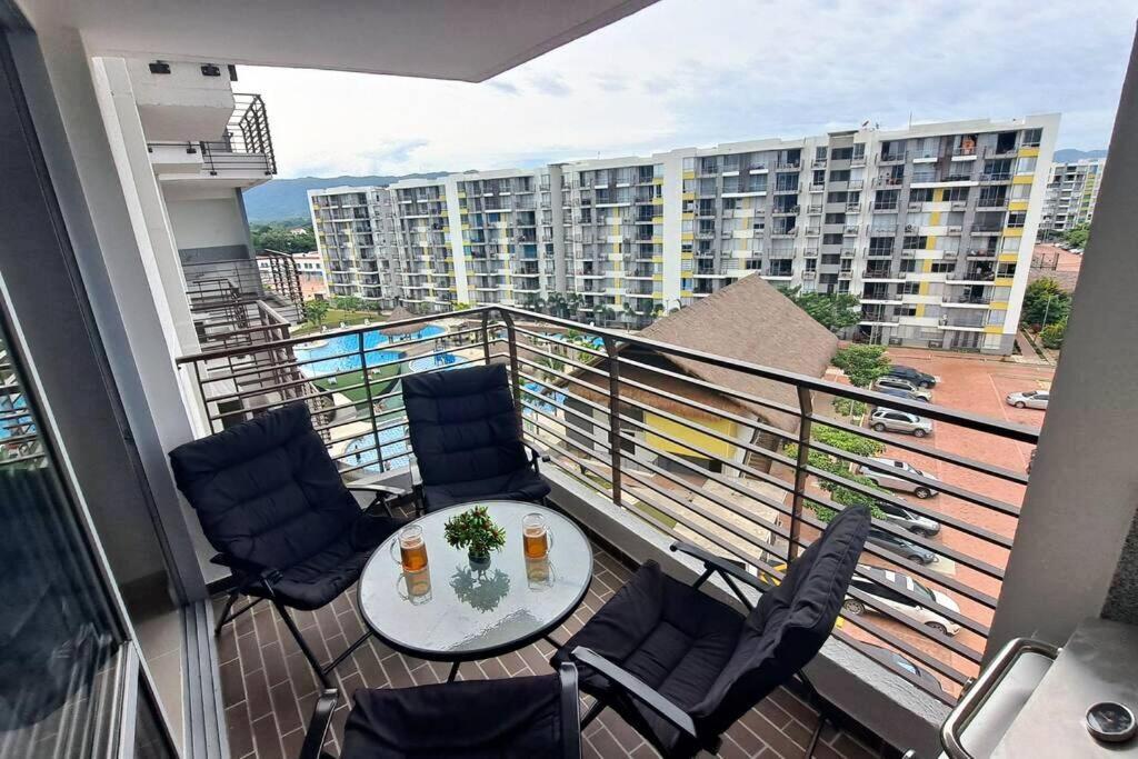 einen Balkon mit einem Tisch und Stühlen sowie ein Gebäude in der Unterkunft Hermoso apt con BBQ en balcon y Vista a la piscina in Ricaurte
