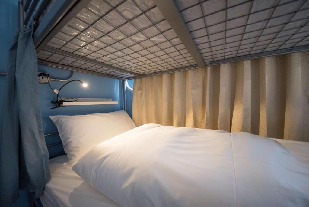 Bett in einem Zimmer mit einem großen weißen Bett in der Unterkunft Deer Traveler Hostel in Yuchi