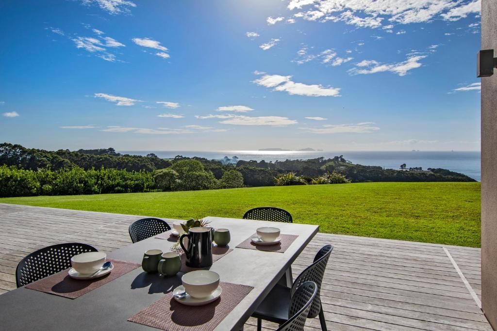 a table on a deck with a view of the ocean at Tutukaka Vista - Tutukaka Holiday Home in Tutukaka