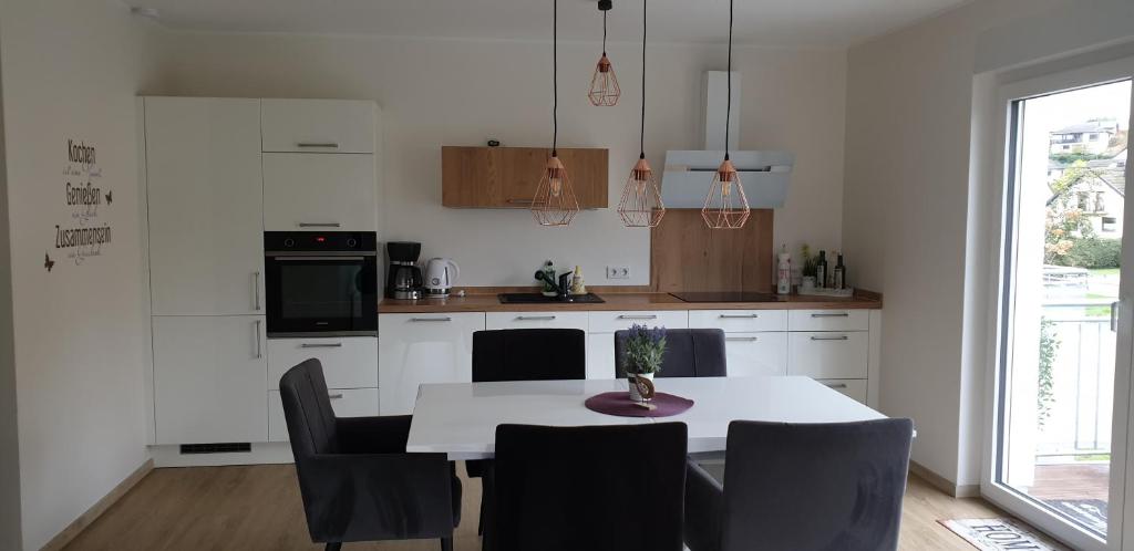 a kitchen with a table and chairs and a kitchen with white cabinets at Ferienwohnung Selina in Losheim