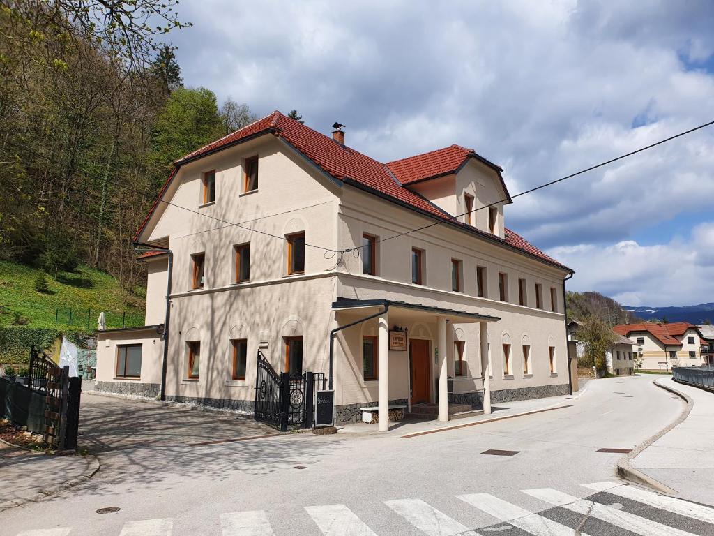 a large white building with a red roof on a street at Rooms Kozmus in Brestanica