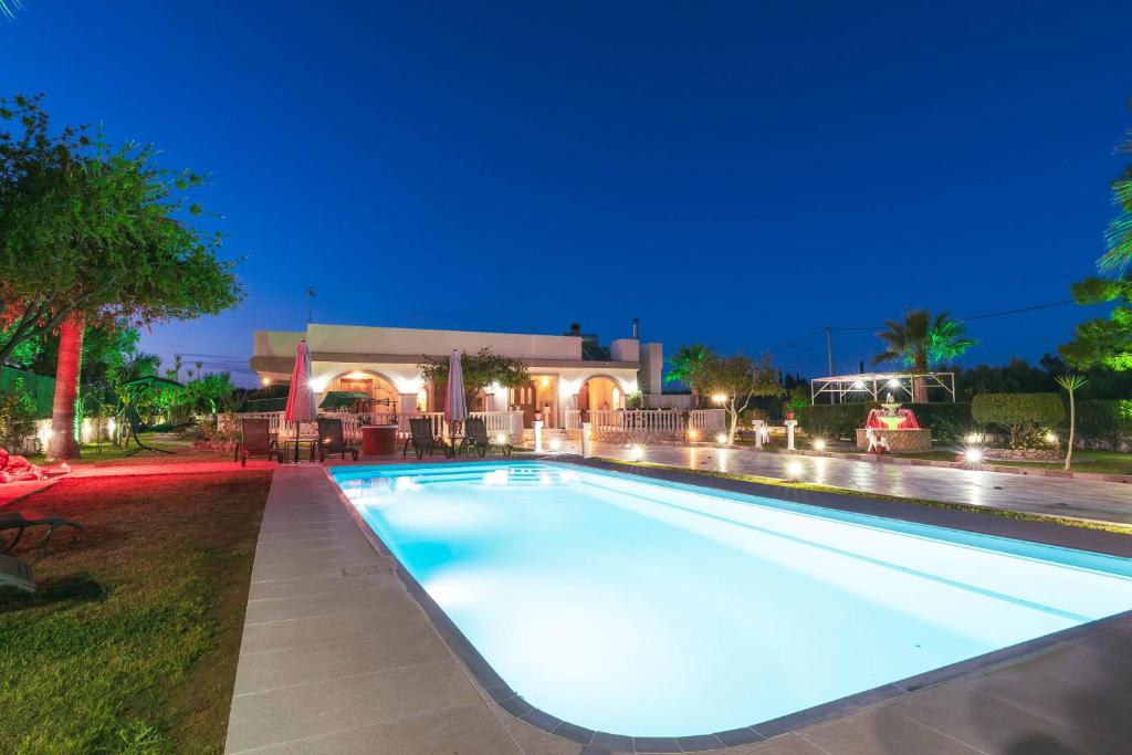 a swimming pool at night with a house in the background at Fontana Holiday Home in Mouzákion