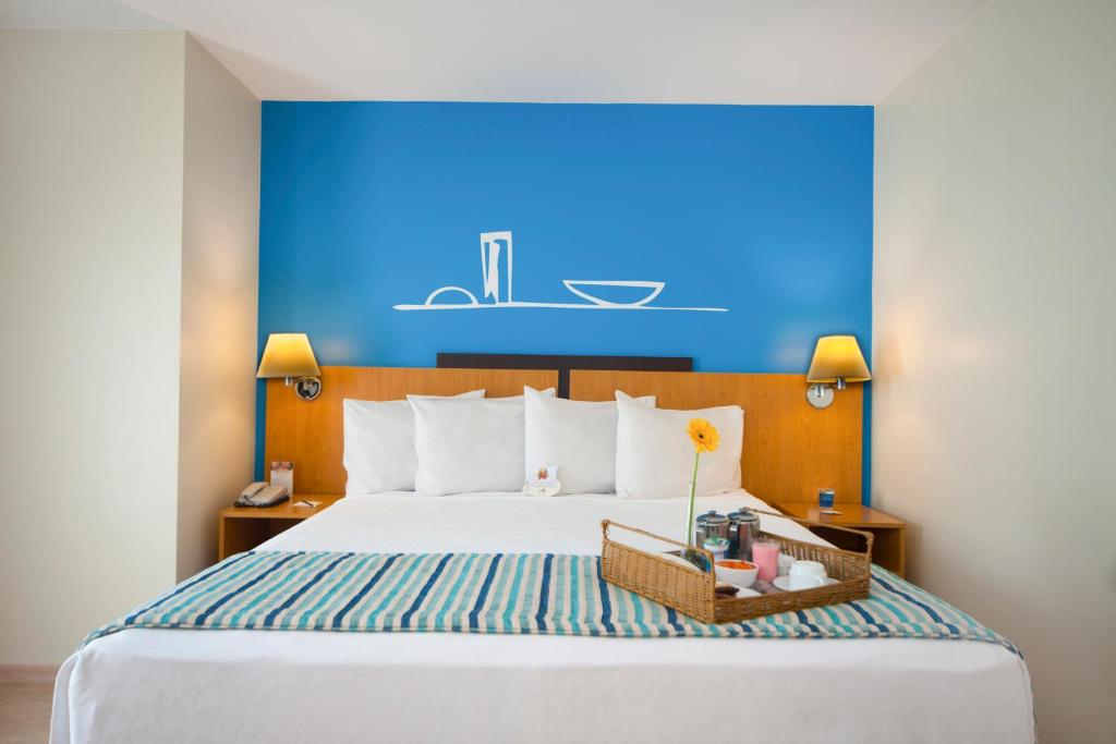 a bedroom with a large bed with a blue wall at Comfort Hotel Taguatinga in Taguatinga