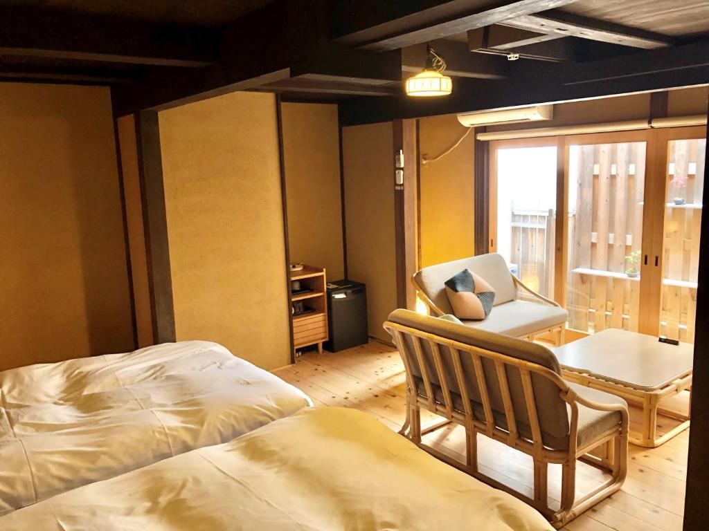 a room with two beds and a chair and a window at Kariya Ryokan Q in Ako