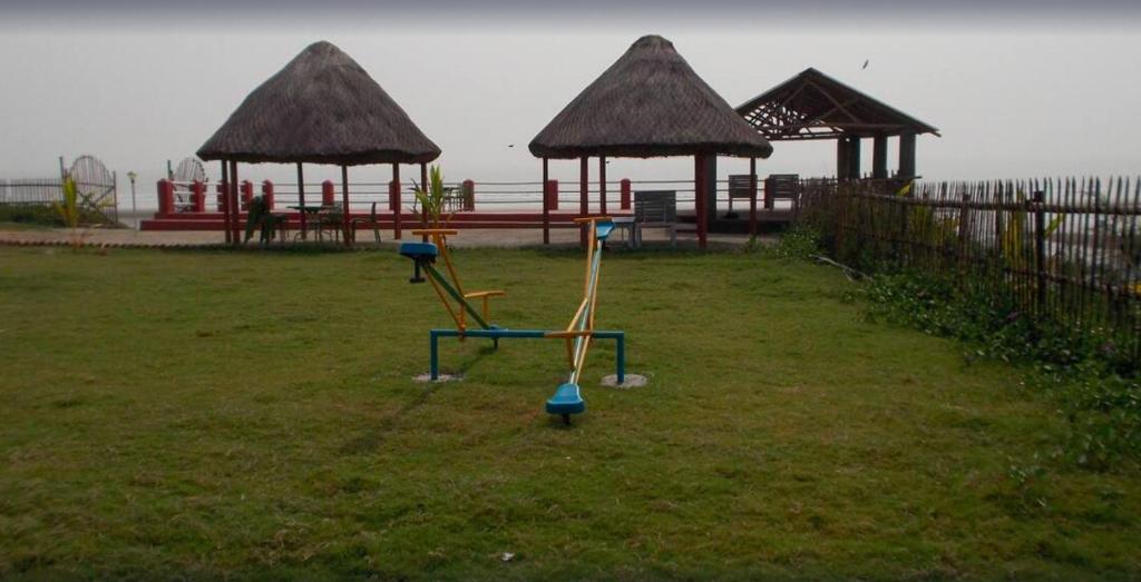 a park with two play equipment in the grass at Arya Beach resort in Mandarmoni