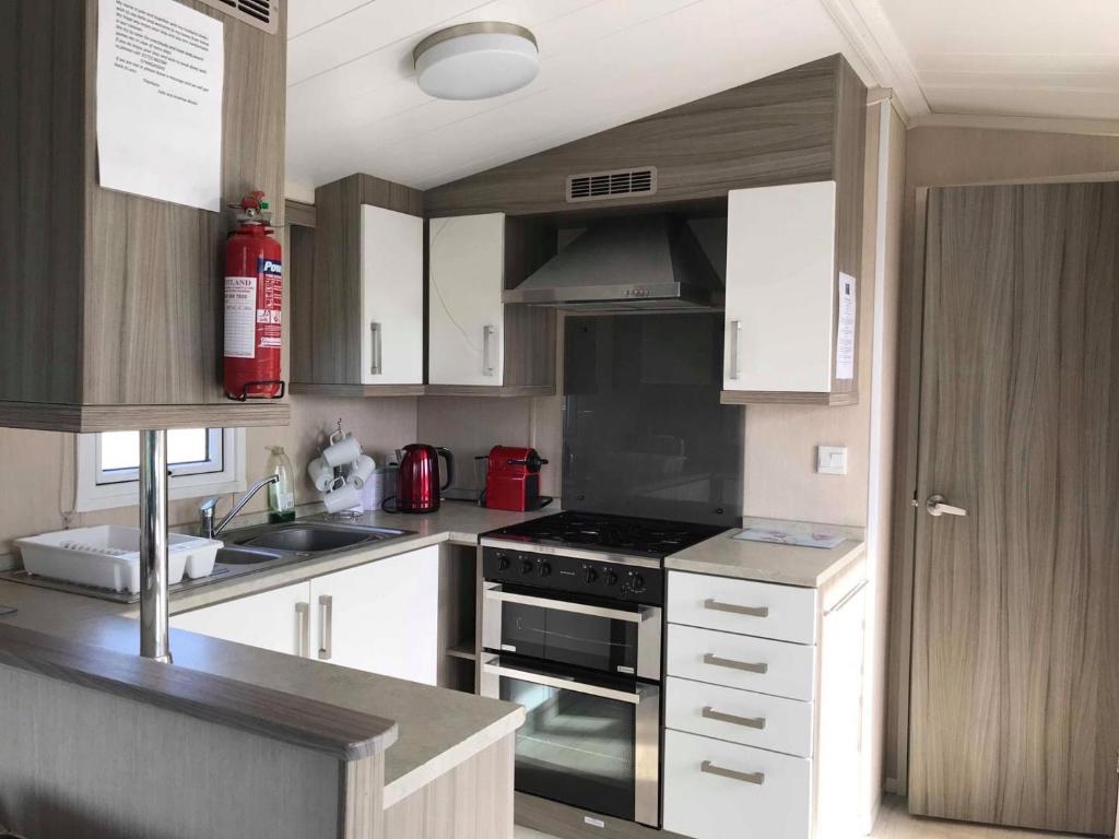 uma cozinha com armários brancos e um forno com placa de fogão em Lime crescent golden sands em Mablethorpe