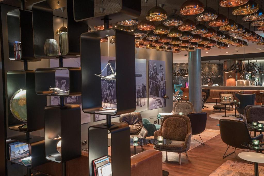 a lobby of a restaurant with chairs and tables at Motel One Hamburg Airport in Hamburg