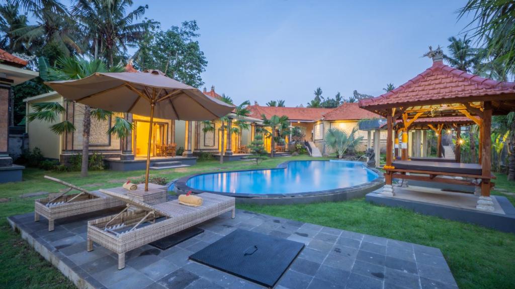 a backyard with a swimming pool and an umbrella at Abhirama Villas by Supala in Ubud