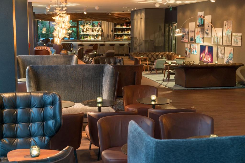 a restaurant with chairs and tables and a bar at Motel One Hamburg-Alster in Hamburg