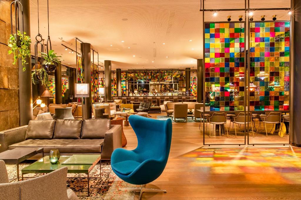 a lobby with a blue chair and a bar at Motel One Köln-Neumarkt in Cologne