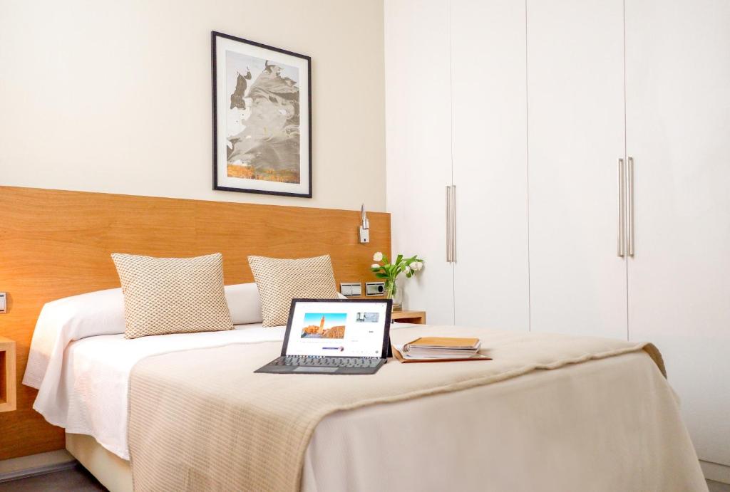a bedroom with a bed with a laptop on it at U-Sense Sevilla Catedral in Seville