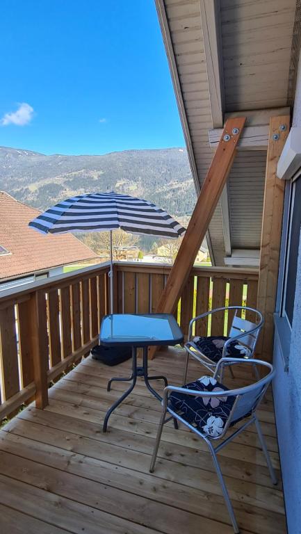 a patio with two chairs and an umbrella on a deck at Ferienwohnungen Claudia in Altossiach