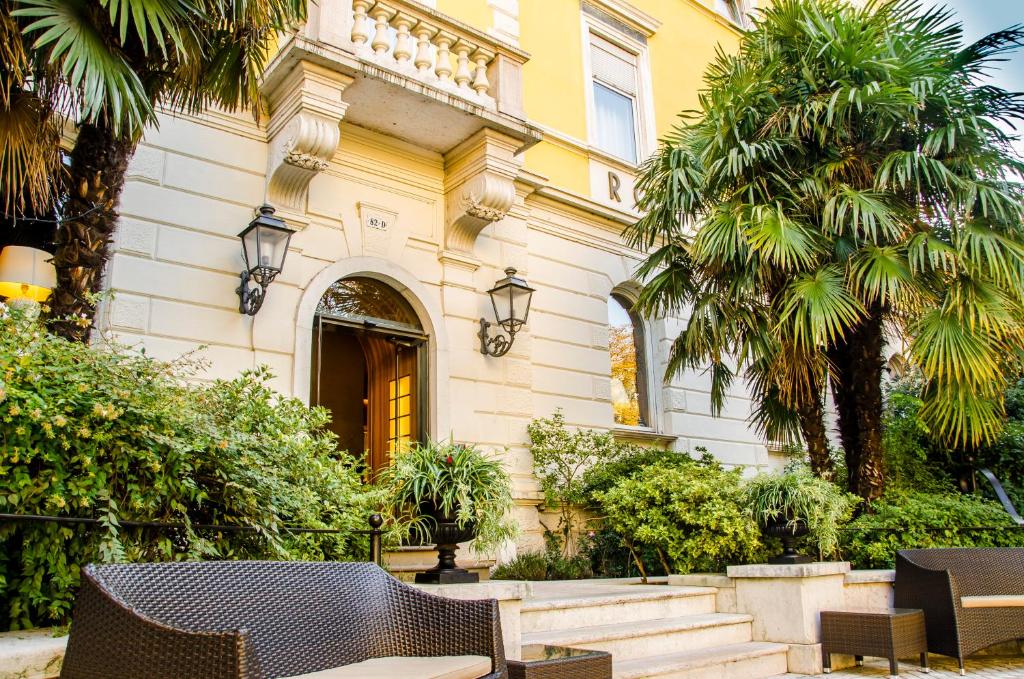 ein Gebäude mit Stühlen und Palmen davor in der Unterkunft Hotel Rovereto in Rovereto