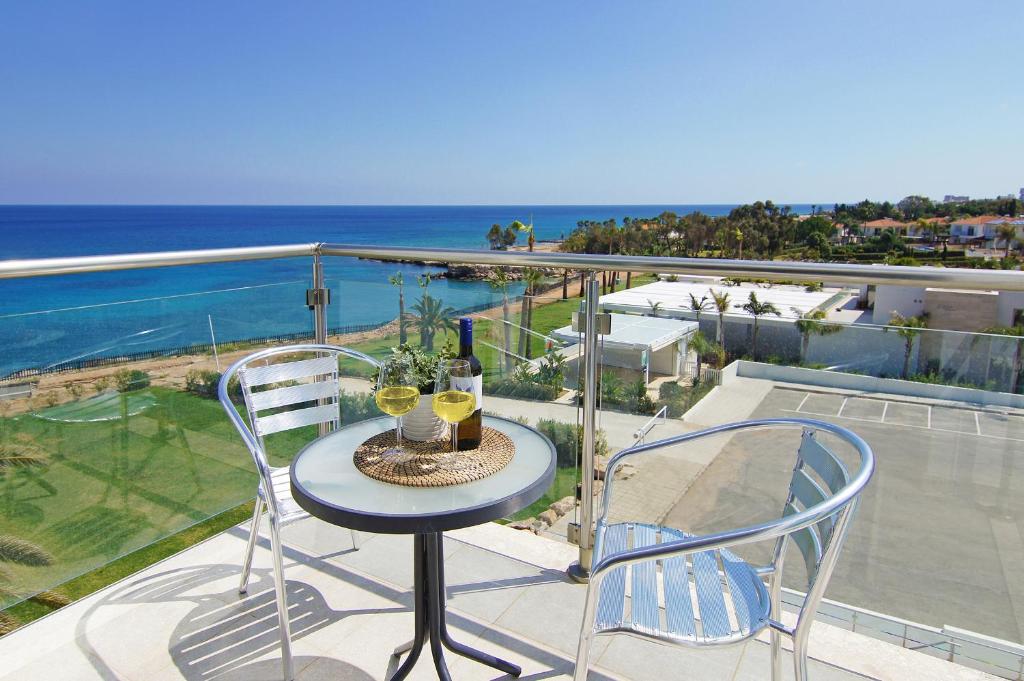 a table with two chairs and wine glasses on a balcony at Apartment Erika in Protaras