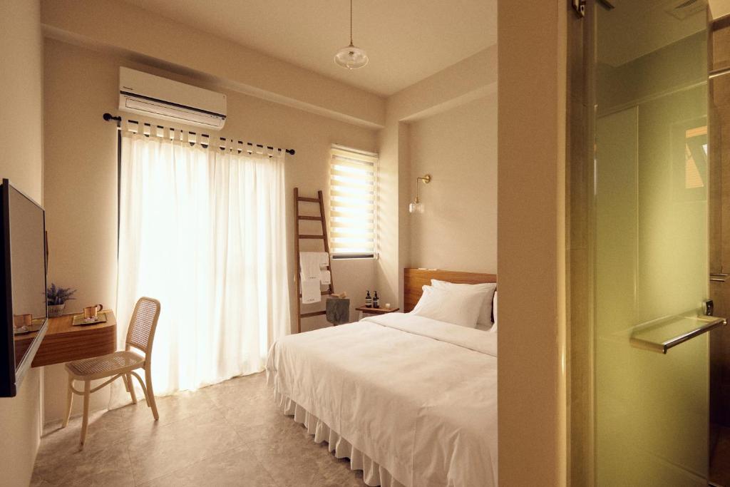 een slaapkamer met een bed, een bureau en een raam bij Sunlight Homestay in Magong