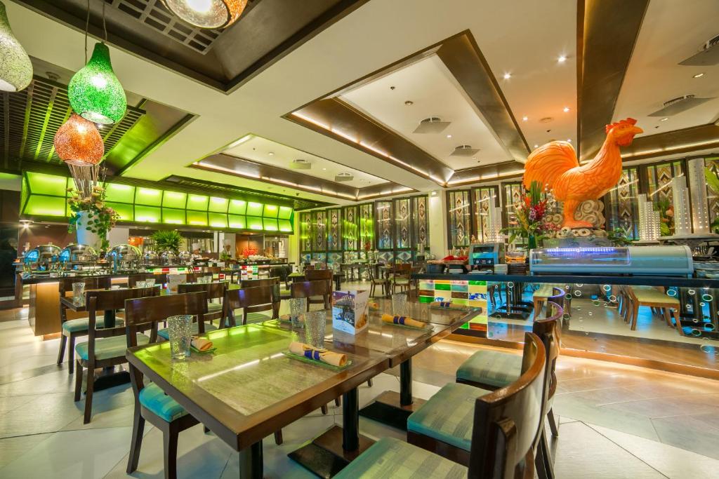 a restaurant with tables and chairs and a chicken statue at Waterfront Airport Hotel and Casino in Mactan