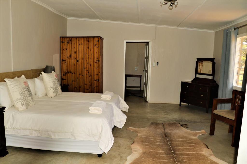 sypialnia z dużym białym łóżkiem i krzesłem w obiekcie Bayala Nyala Breeders Private Game Reserve w mieście Mkuze