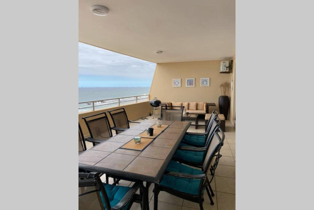 un comedor con mesa y sillas y el océano en 32 Lazy Lizard - Beautiful Sea Viewing Apartment en Umdloti