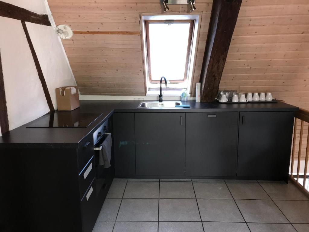 格平根的住宿－MONTEURWOHNUNG - Gesamtes Apartment，厨房配有黑色橱柜、水槽和窗户。