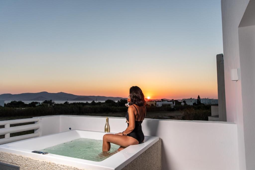 uma mulher sentada numa banheira a ver o pôr-do-sol em Villa Gold & White em Maragkas