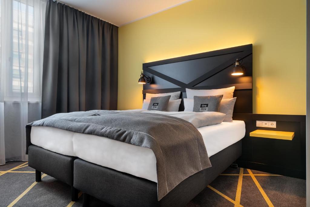 een slaapkamer met een groot bed met gele muren bij the niu Fury - Apartments in Aschheim