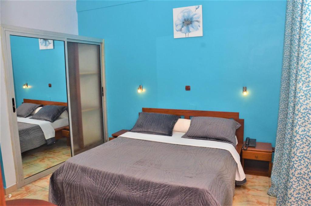 Dormitorio azul con cama y espejo en Hotel - Y en Douala