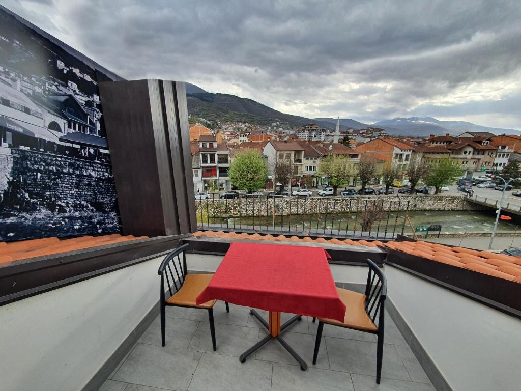 una mesa roja y sillas en un balcón con vistas en Hotel Oferta en Prizren