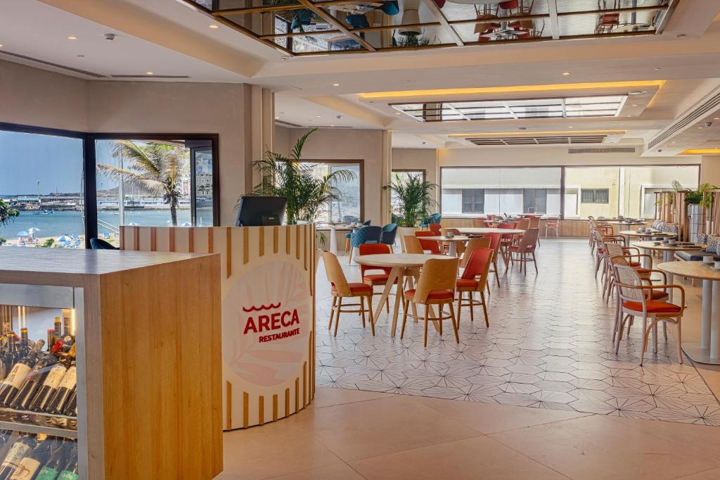a restaurant with tables and chairs in a cafeteria at Hotel Cristina by Tigotan Las Palmas - Adults Only in Las Palmas de Gran Canaria