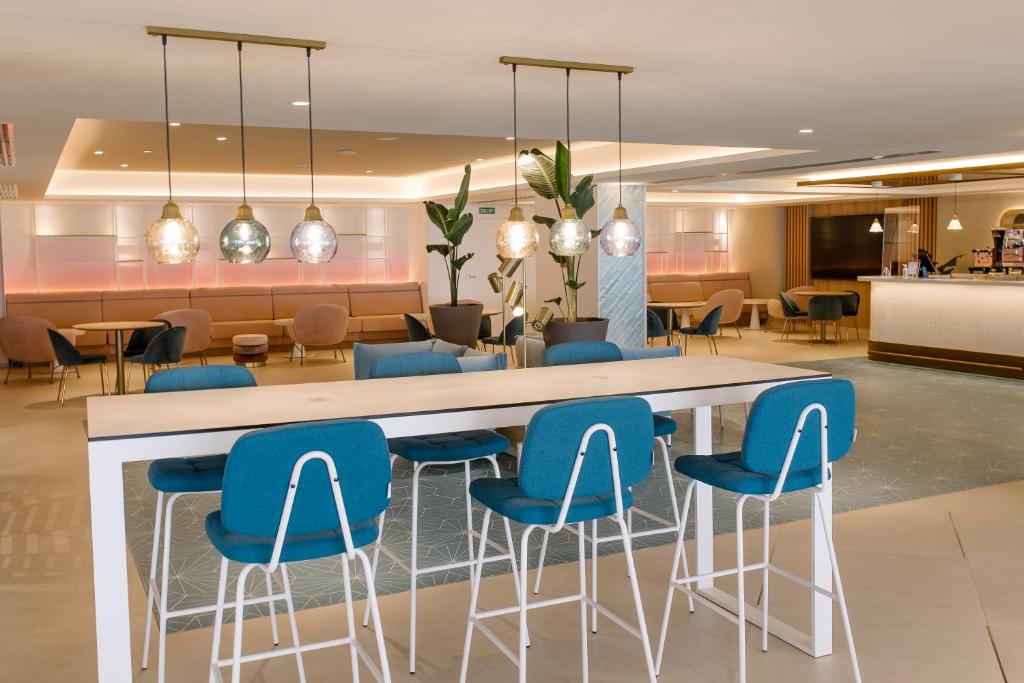 a lobby with a bar with blue chairs at Hotel Cristina by Tigotan Las Palmas - Adults Only in Las Palmas de Gran Canaria