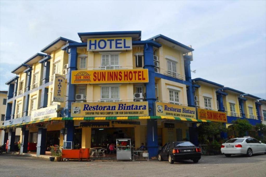 Kampong Batu Lapan的住宿－Sun Inns Tambun，一条街道上的酒店,门前有车辆停放
