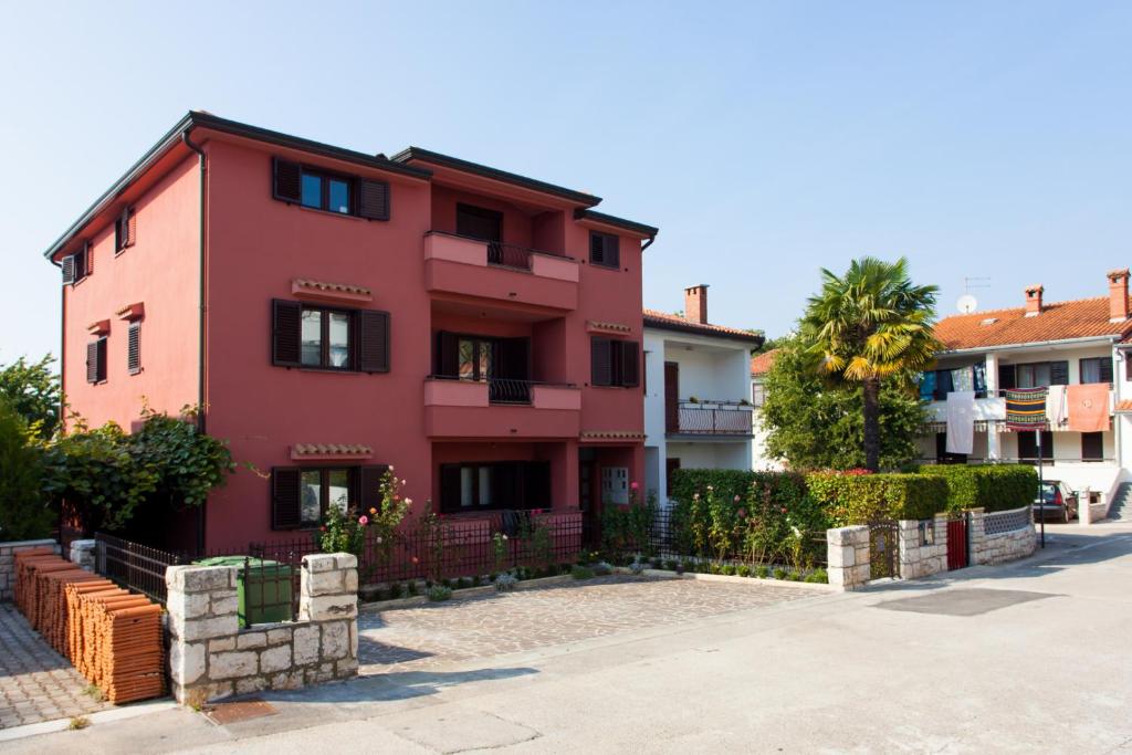 a pink house with a fence in front of it at Apartments Banić in Poreč