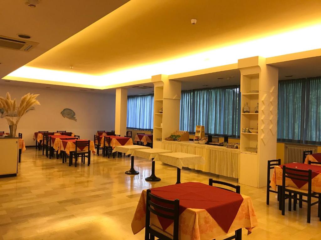 a restaurant with tables and chairs and windows at Hotel Senio in Riolo Terme
