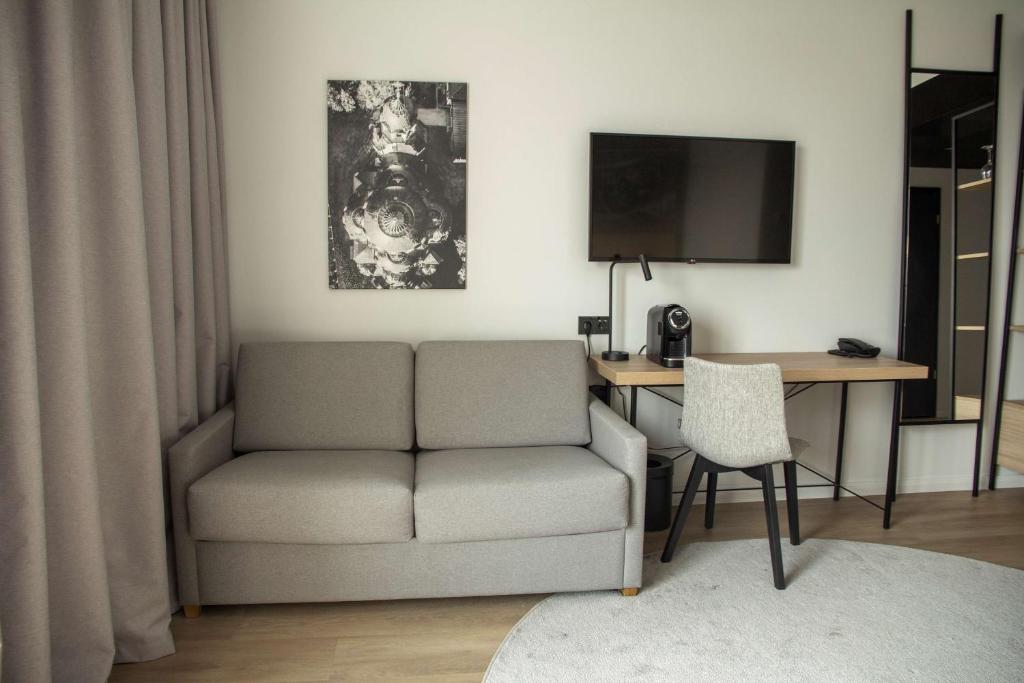a living room with a couch and a desk with a television at Park Inn by Radisson Vilnius Airport Hotel & Conference Centre in Vilnius